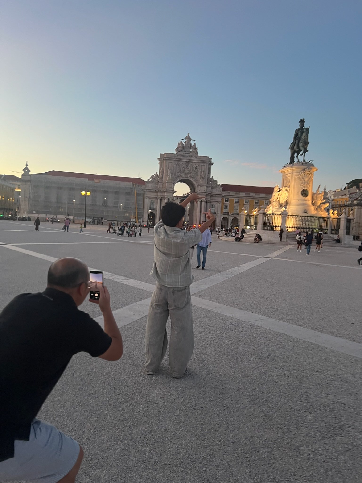 Dad crouching to line up a phone photo in Praça do Comércio